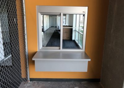 Glass window and a small white desk attached built into a small orange wall