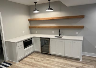 White wood cabinets designed and created by MAC with a mini fridge