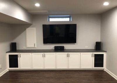 White cabinets under a countertop with a TV hanging above it