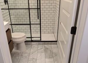 Bath room with glass shower and dark wood cabinets designed by MAC with white tile flooring