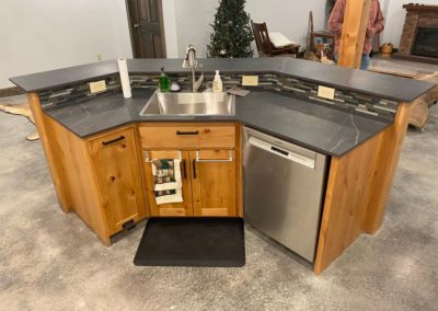 Dark wood cabinets made by MAC under black marble countertop with silver appliances
