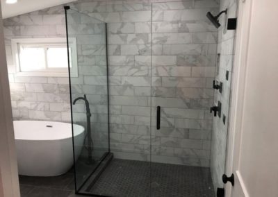 Glass shower with custom black tiling and white bathtub installed by MAC in Kansas City