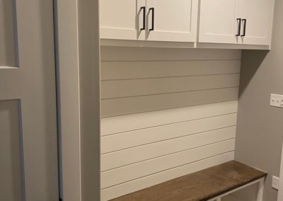 White cabinets in a storage space with light wood flooring
