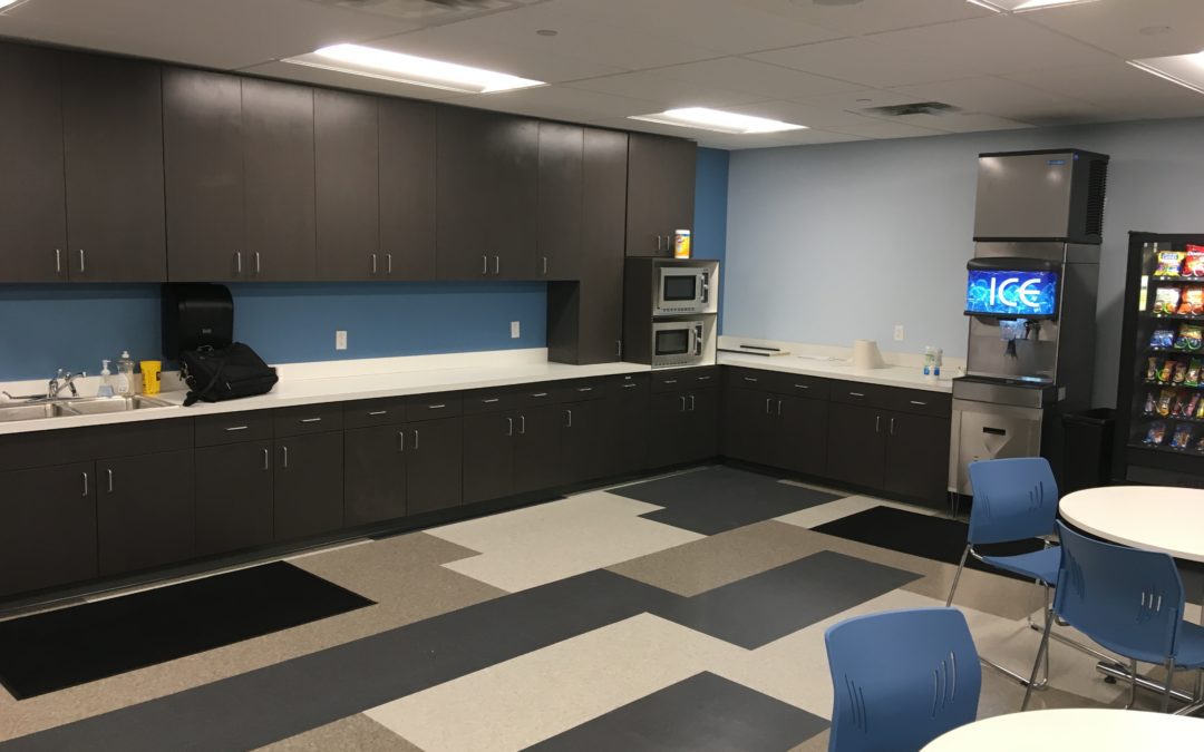 Black cabinets installed by MAC in Kansas City,in a break room with ice and vending machine along with white tables and blue chairs